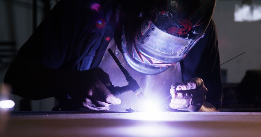 Skilled Welder Working with Intense Light in Dark Workshop - Free Images, Stock Photos and Pictures on Pikwizard.com