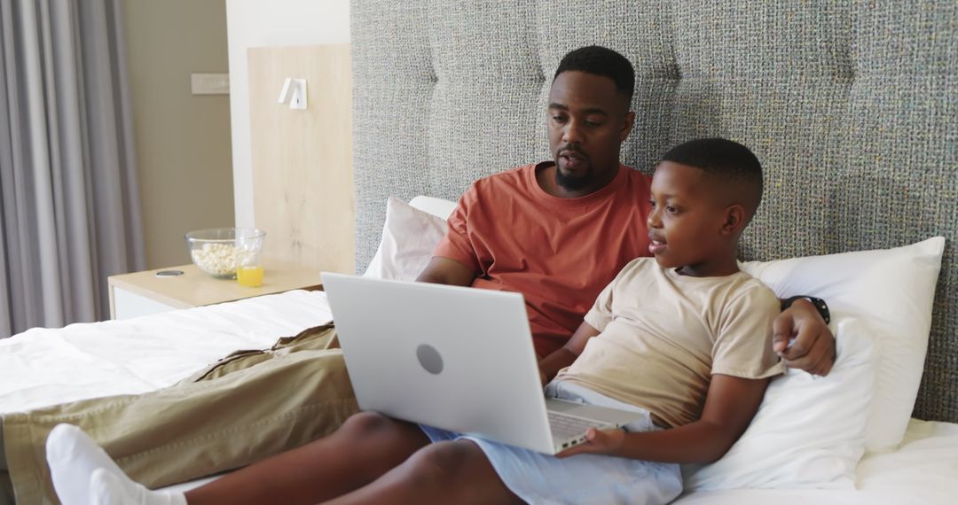 Father and Son Using Laptop on Comfortable Bed