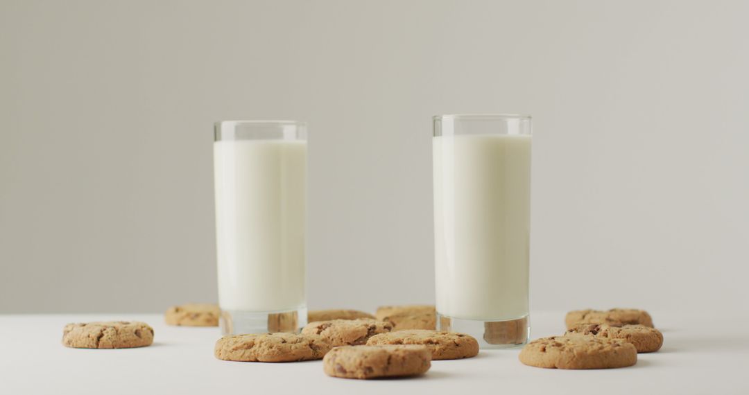 Two Glasses of Milk with Chocolate Chip Cookies on White Table - Free Images, Stock Photos and Pictures on Pikwizard.com