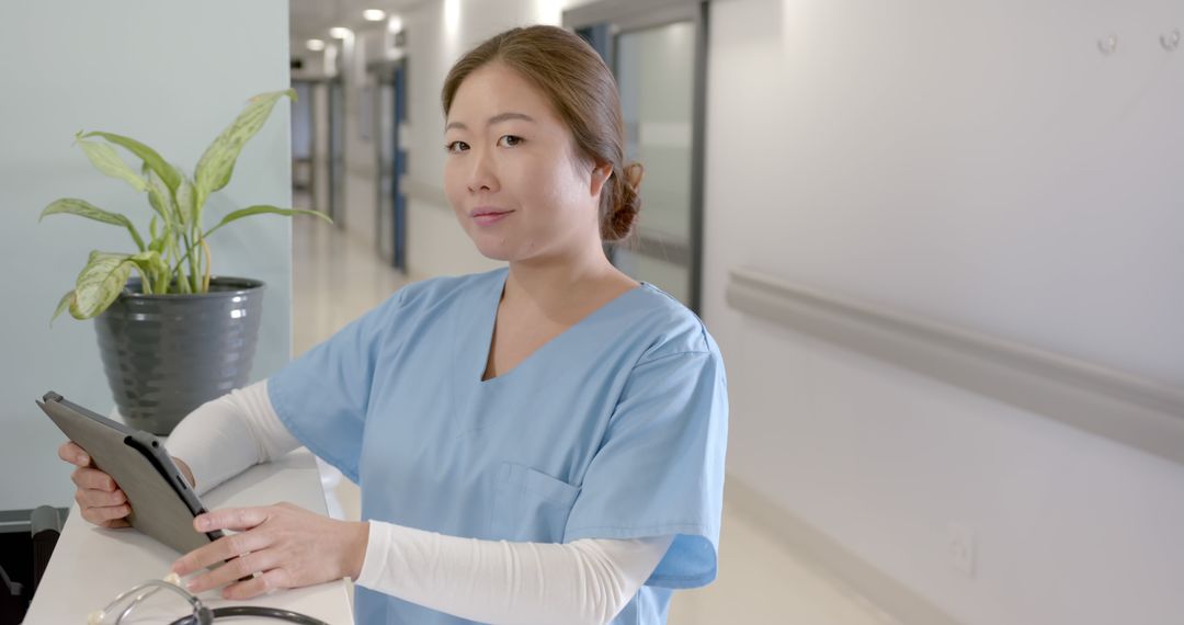 Confident Nurse Holding Tablet in Hospital Corridor - Free Images, Stock Photos and Pictures on Pikwizard.com