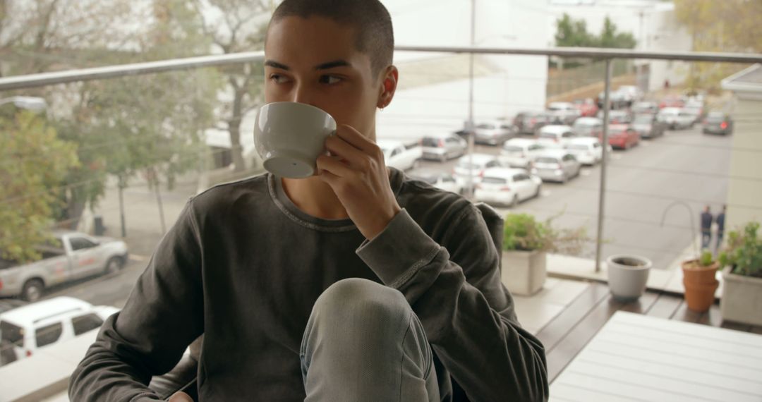 Young Man Drinking Coffee on Outdoor Balcony in Urban Setting - Free Images, Stock Photos and Pictures on Pikwizard.com