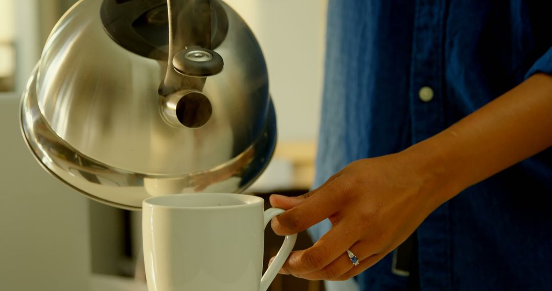 Close-Up of Young African American Woman Pouring Hot Water from Kettle into White Mug - Free Images, Stock Photos and Pictures on Pikwizard.com