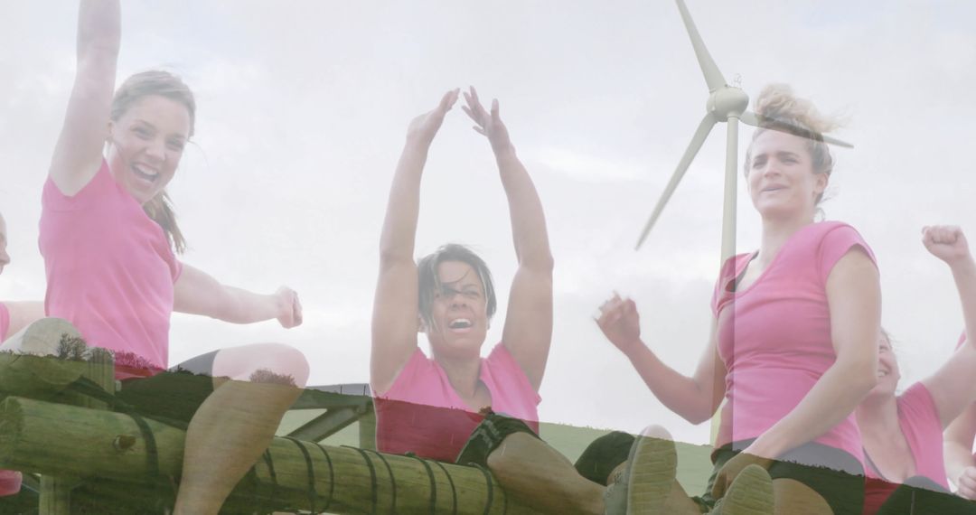 Women Cheering on Log Obstacle with Wind Turbine at Renewables Event