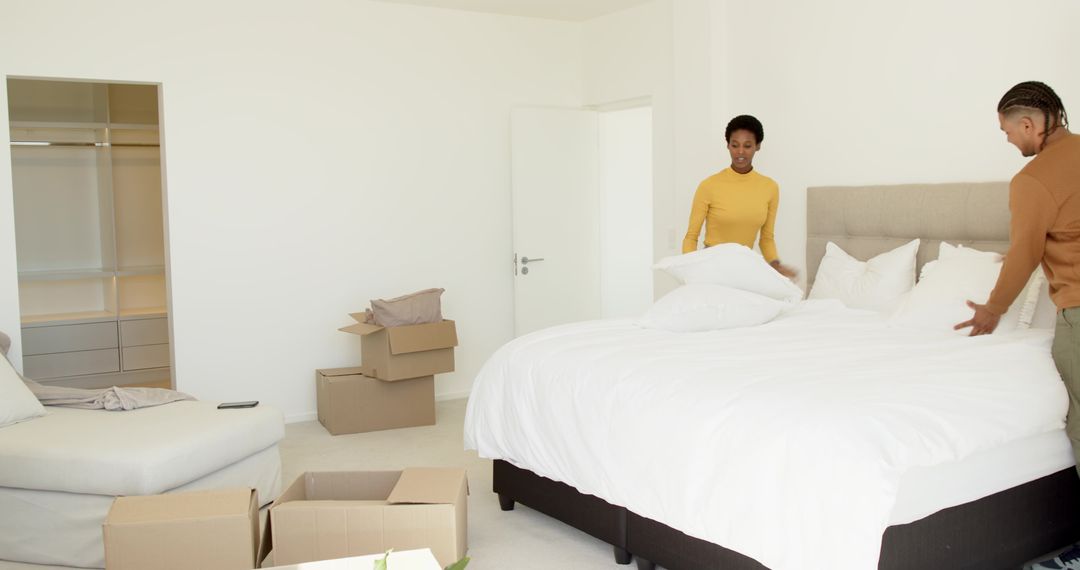 Couple Organizing Bed During Home Move with Minimalist Decor