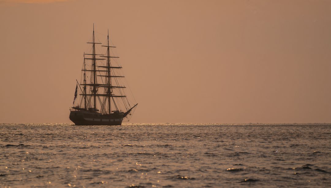 Majestic Three-Masted Ship Transitioning Ocean at Golden Sunset
