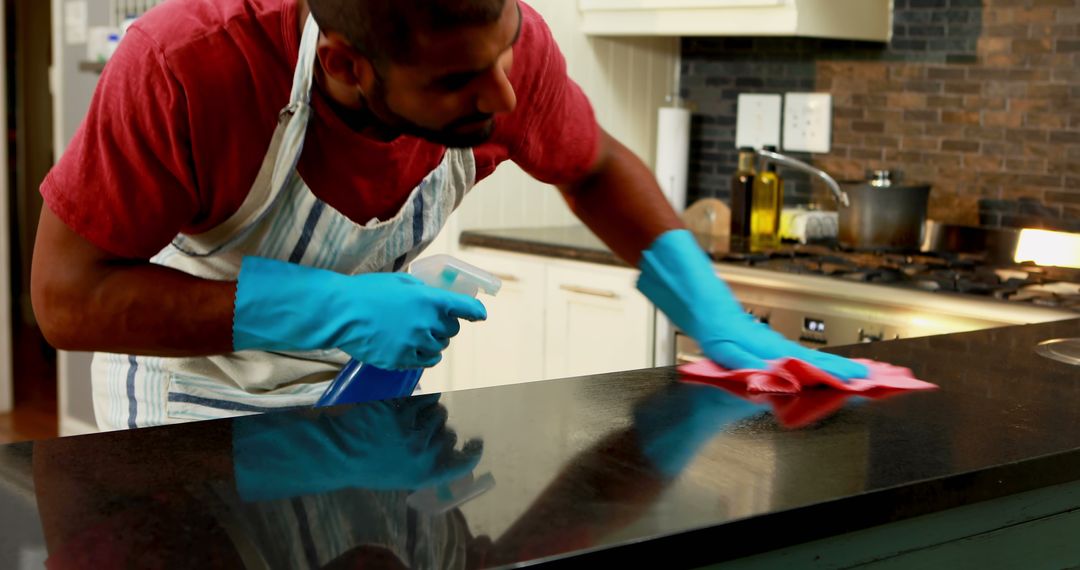 Man Cleaning Kitchen Countertop with Spray Bottle and Cloth - Free Images, Stock Photos and Pictures on Pikwizard.com