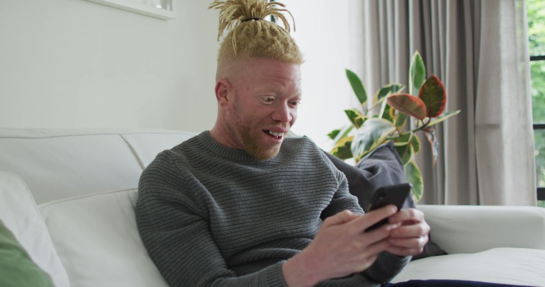 Young Man With Albinism Using Smartphone At Home - Free Images, Stock Photos and Pictures on Pikwizard.com