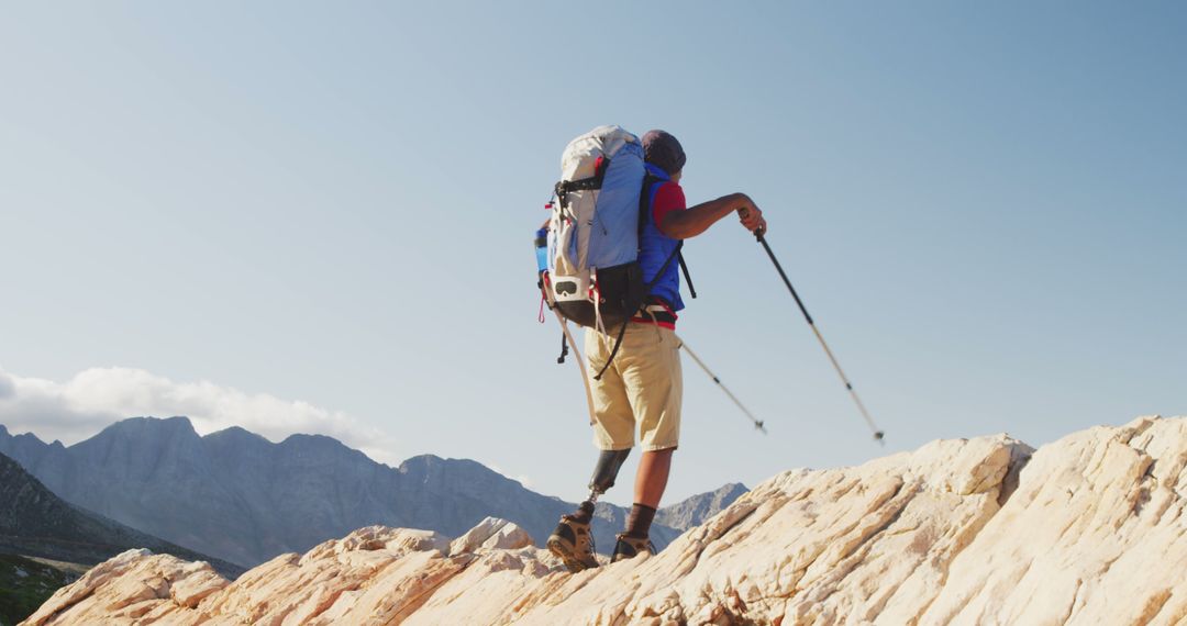 Man Hiking On Rocky Mountain Summit With Trekking Poles - Free Images, Stock Photos and Pictures on Pikwizard.com