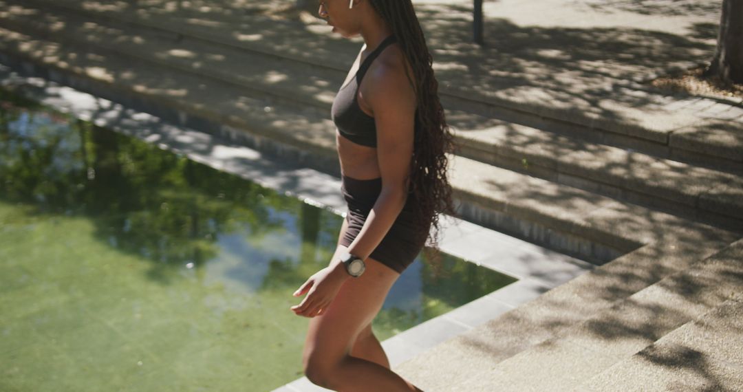 Female athlete walking by pool in sportswear on sunny day - Free Images, Stock Photos and Pictures on Pikwizard.com