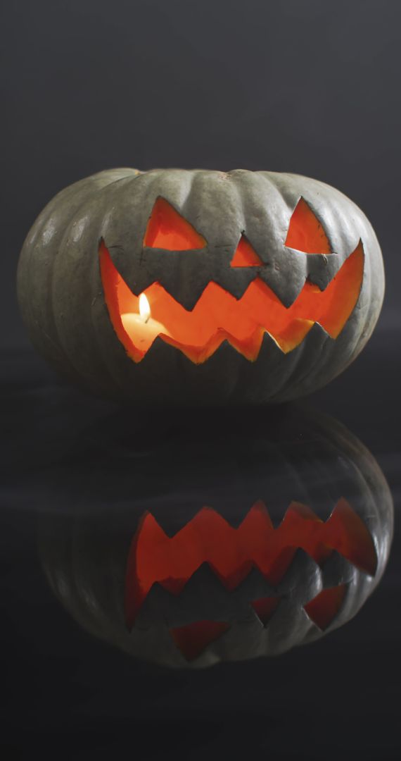 Lit Carved Halloween Pumpkin with Glowing Smile on Grey Background - Free Images, Stock Photos and Pictures on Pikwizard.com