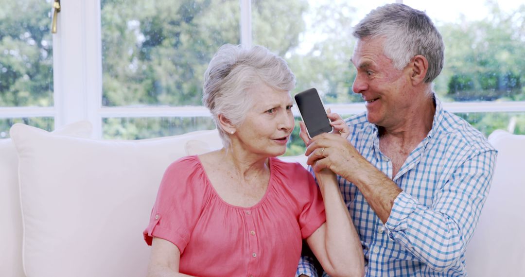 Happy Senior Couple Enjoying Smartphone Together on Couch - Free Images, Stock Photos and Pictures on Pikwizard.com