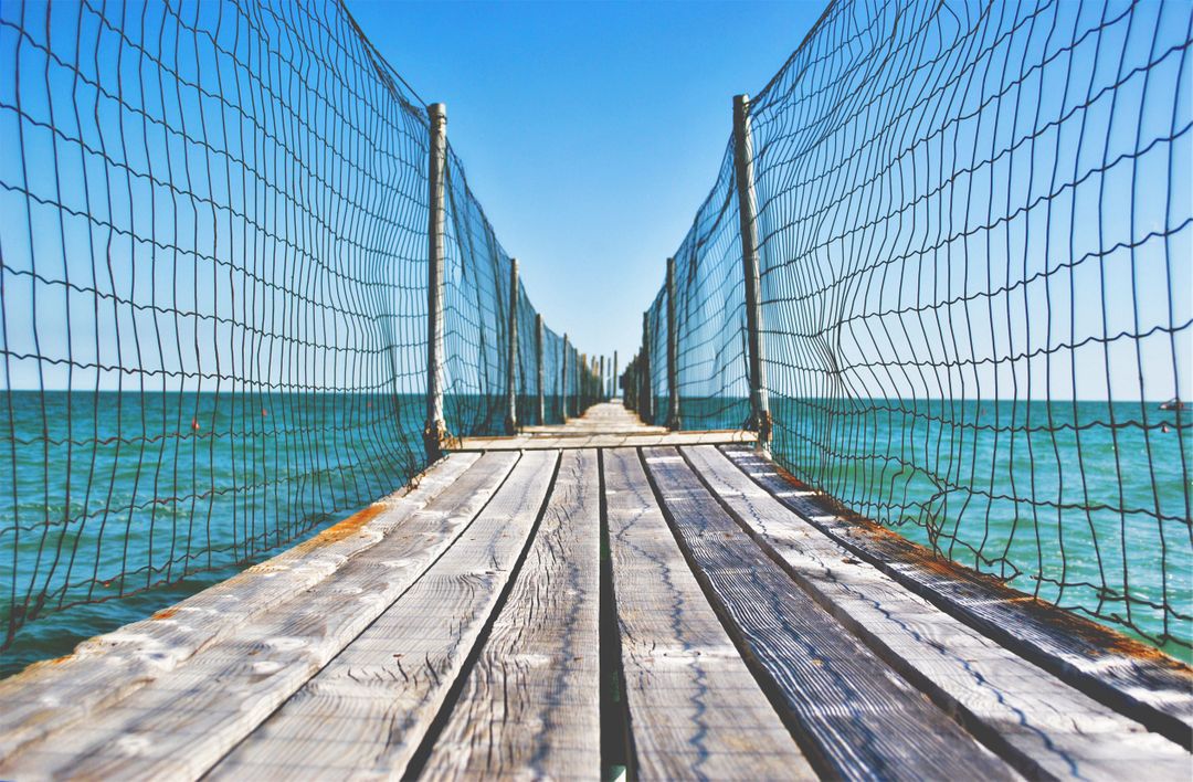 Wooden Pier Extending into Seascape with Net Fencing - Free Images, Stock Photos and Pictures on Pikwizard.com