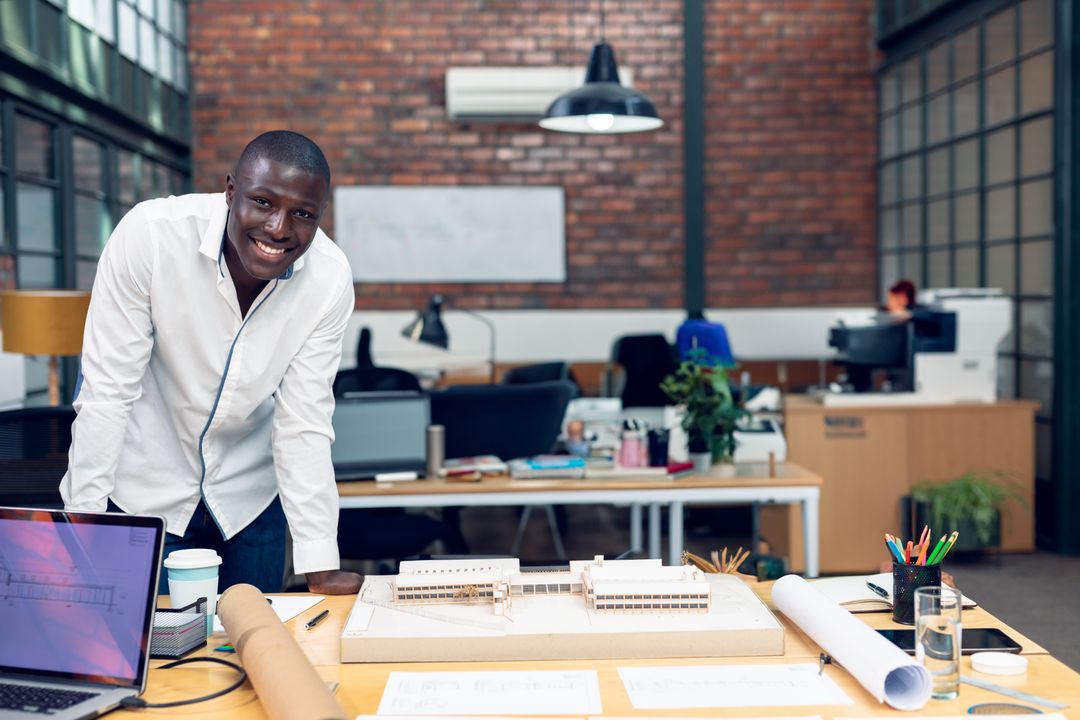 Smiling Architect Leaning Over Desk Showcasing Architectural Model