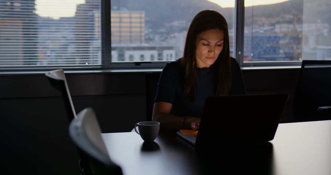 Focused Businesswoman Using Laptop in Modern Office During Evening