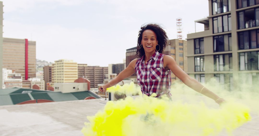Cheerful African American Woman Playing with Colored Smoke Bomb on Rooftop - Free Images, Stock Photos and Pictures on Pikwizard.com