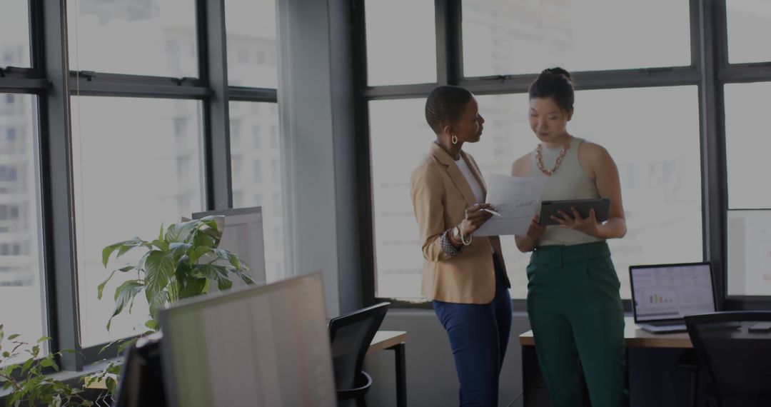 Two Businesswomen Analyzing Reports in Modern Office
