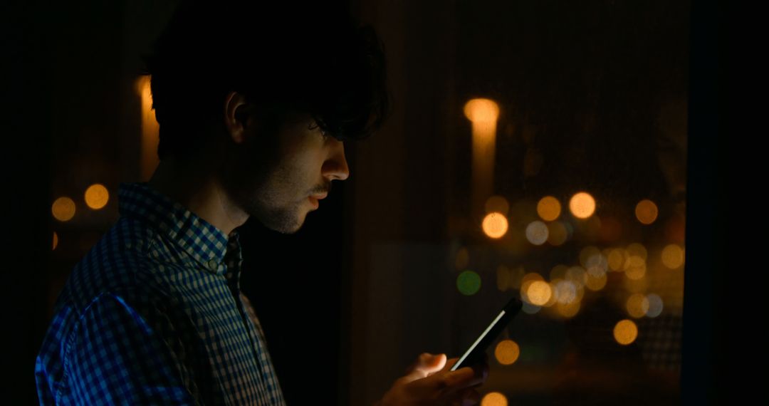 Young Man Using Smartphone at Night with City Lights in Background - Free Images, Stock Photos and Pictures on Pikwizard.com