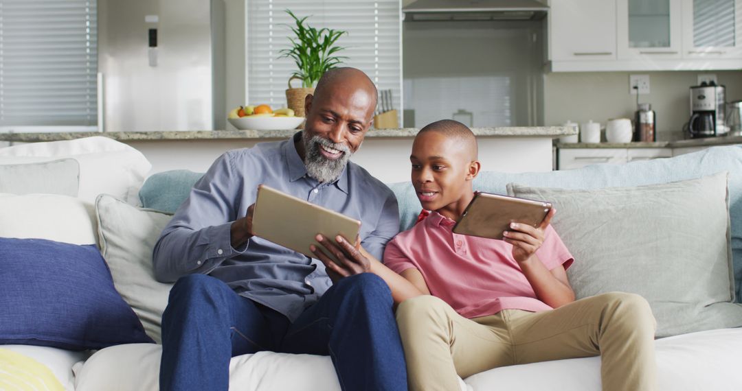 Image of happy african american father and son using tablets together - Free Images, Stock Photos and Pictures on Pikwizard.com