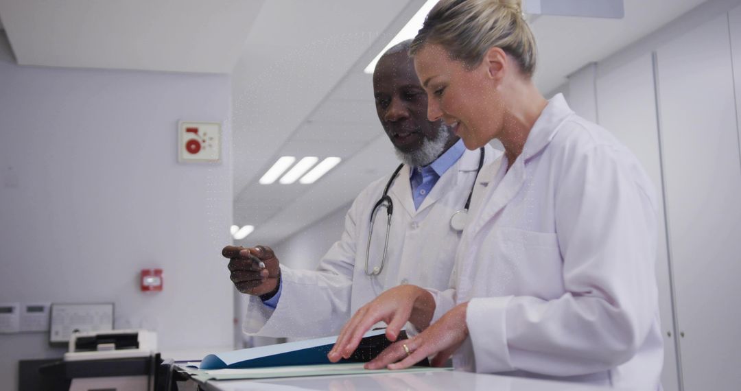 Reviewing Patient File While Collaborating at Nurses Station Doctors Working Together