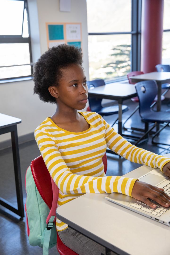 Focused Teenage Student Using Laptop in Bright Classroom