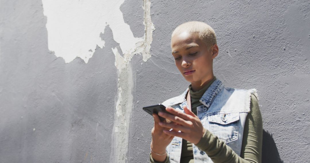 Biracial woman leaning on wall and using smartphone, copy space - Free Images, Stock Photos and Pictures on Pikwizard.com