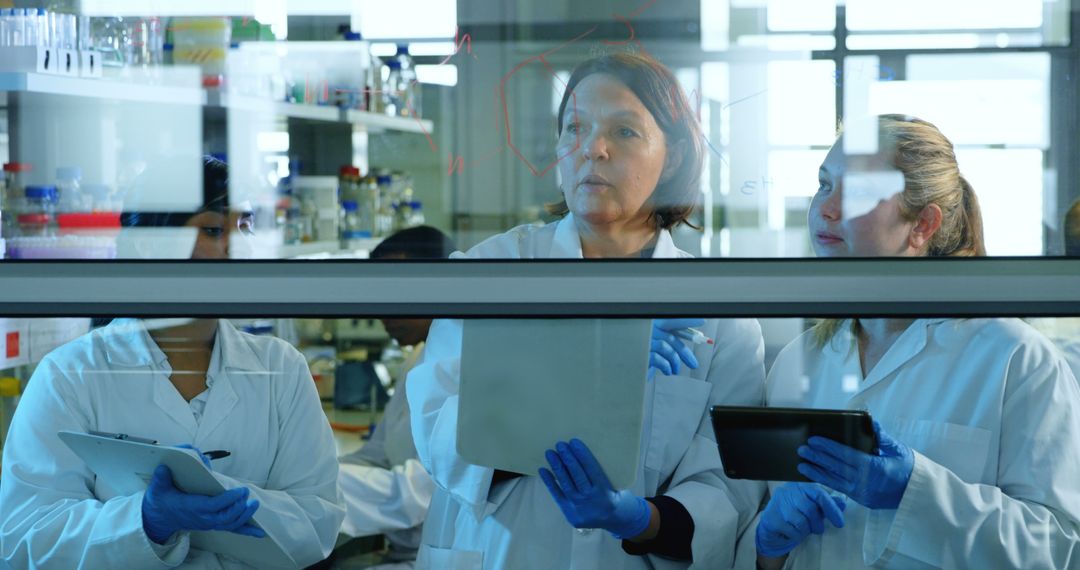 Female Scientists Collaborating Through Laboratory Window on Digital Devices - Free Images, Stock Photos and Pictures on Pikwizard.com