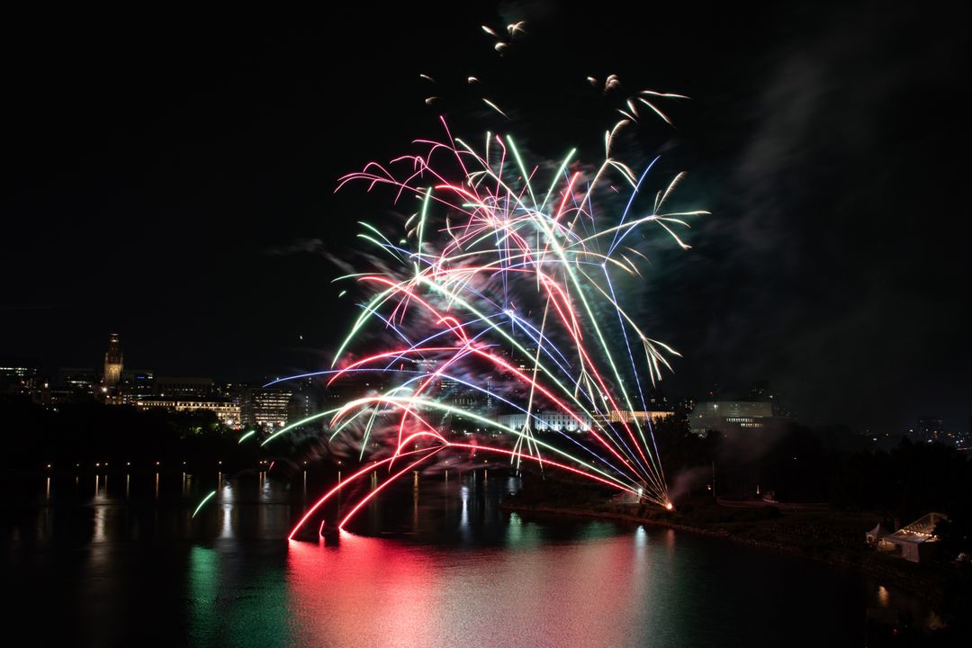 Festive Fireworks Illuminating Riverside Cityscape at Night
