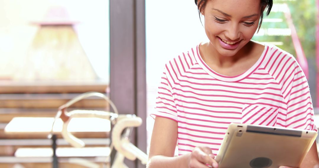 A young African American woman is smiling while using a tablet, with copy space - Free Images, Stock Photos and Pictures on Pikwizard.com