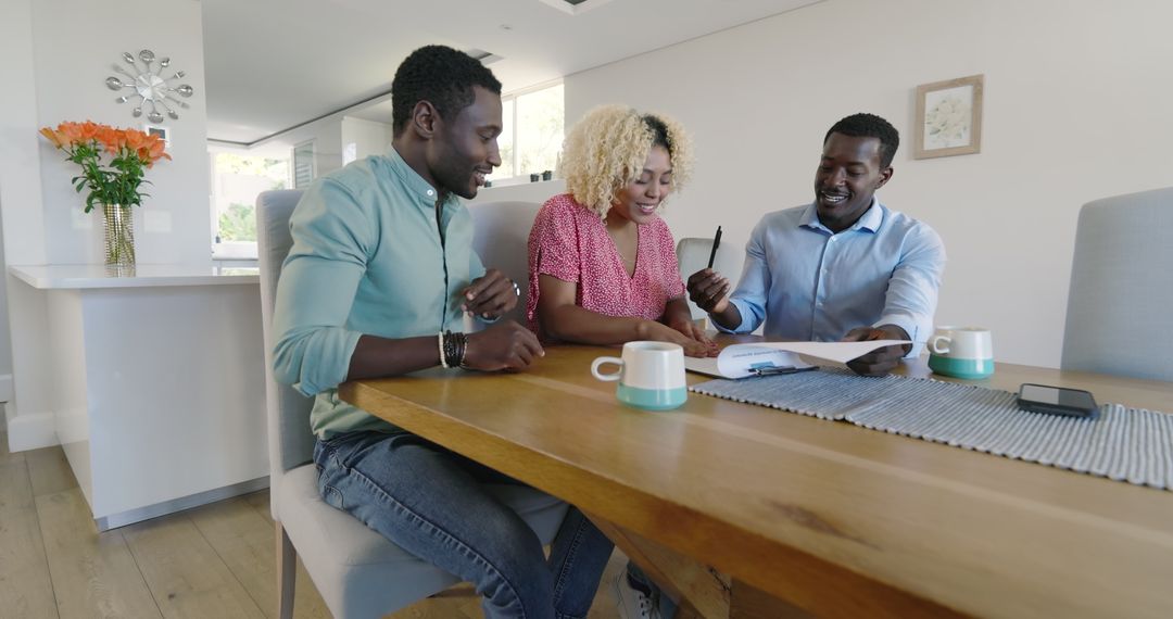 Friends Discussing Documents Around Dining Table at Home
