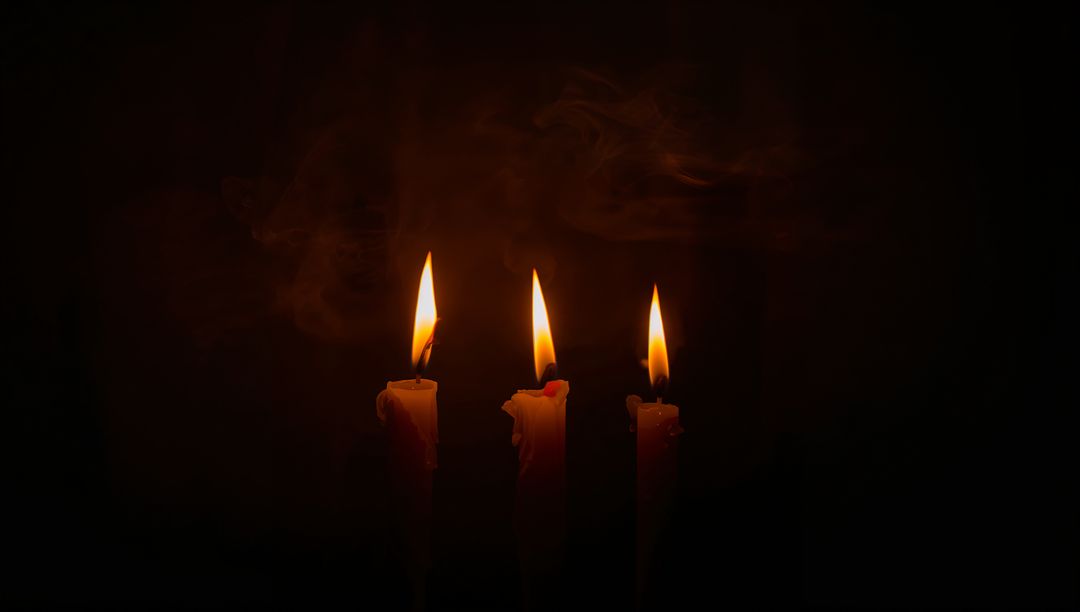 Moody trio of flickering taper candles glowing with warm flames and melting wax drips