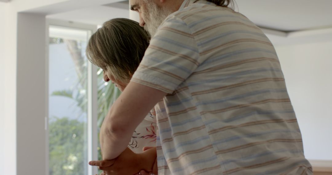 Senior Couple Bonding Together by Large Window in Cozy Home Environment