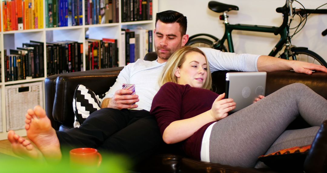 Couple Relaxing on Couch with Smartphone and Tablet in Modern Living Room - Free Images, Stock Photos and Pictures on Pikwizard.com