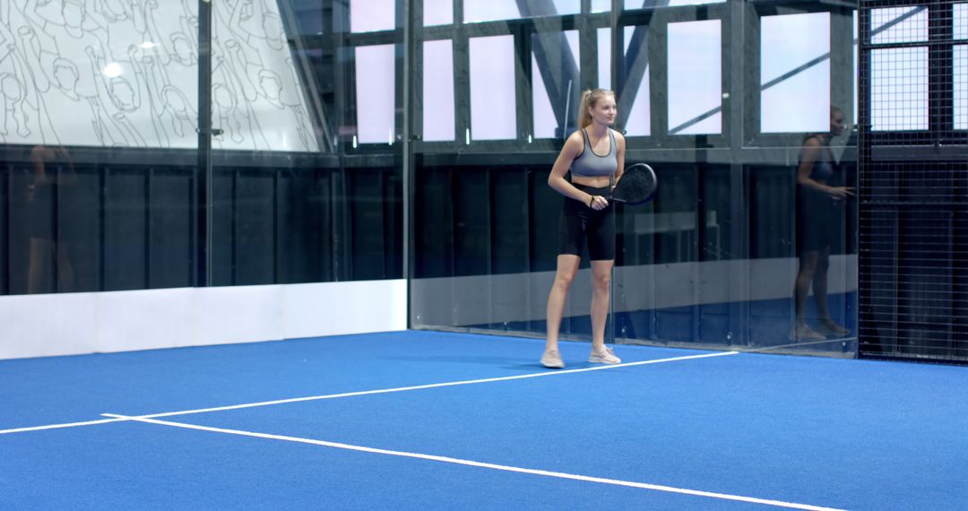 Female Padel Player Preparing to Serve on Indoor Court