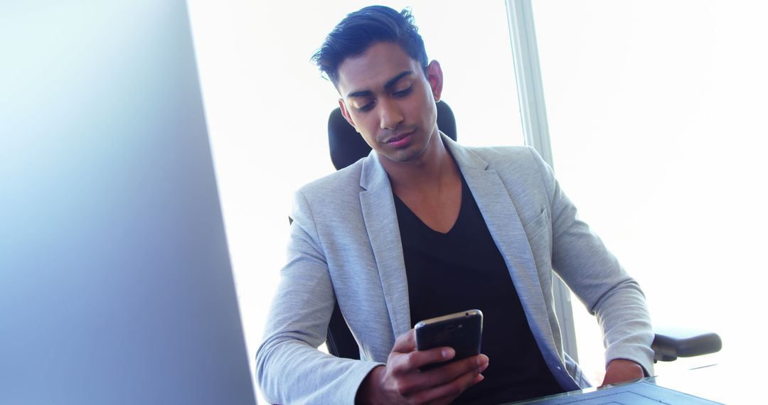 Confident Executive Using Smartphone at Office Desk