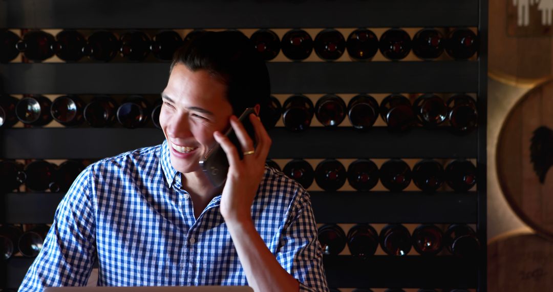 Cheerful Young Man Talking on Smartphone in Wine Cellar - Free Images, Stock Photos and Pictures on Pikwizard.com