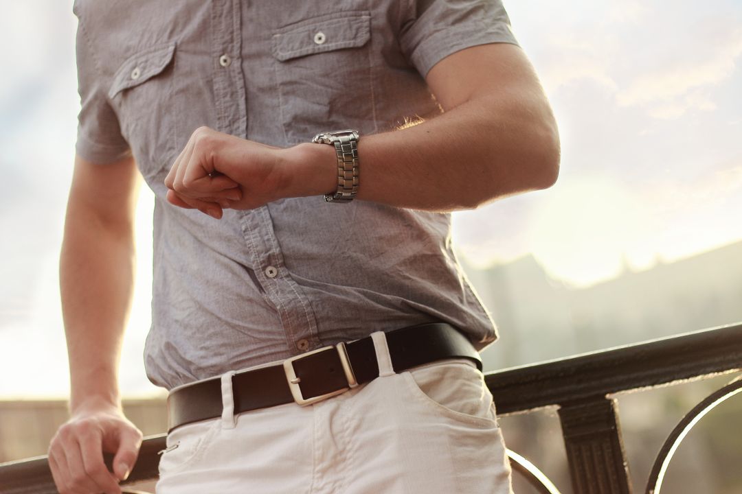 Man Checking Time on Wristwatch Outdoors at Sunset