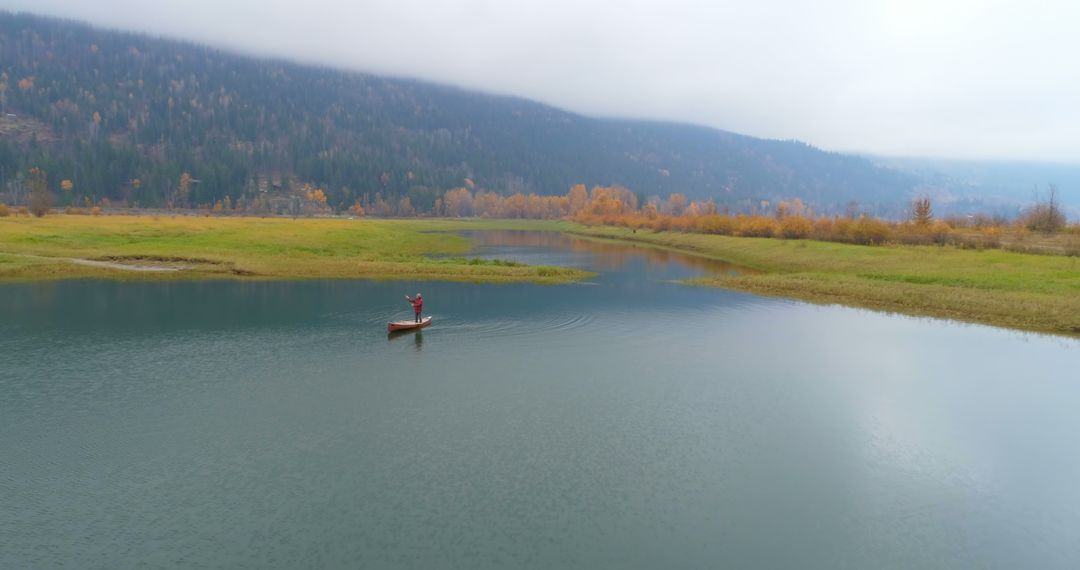 Solitary Person Canoeing on Serene Lake with Mountain Landscape - Free Images, Stock Photos and Pictures on Pikwizard.com