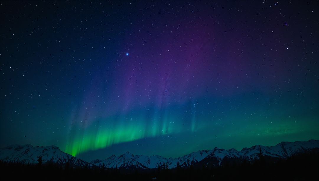 Vibrant northern lights dancing over snow-capped mountains and starry arctic sky