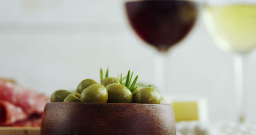 Green Olives in Wooden Bowl with Wine Glasses in Background - Free Images, Stock Photos and Pictures on Pikwizard.com