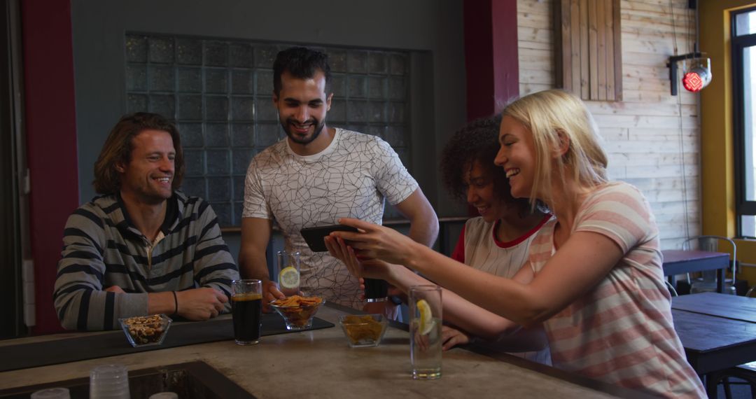 Happy Friends Socializing with Drinks and Smartphone at Bar