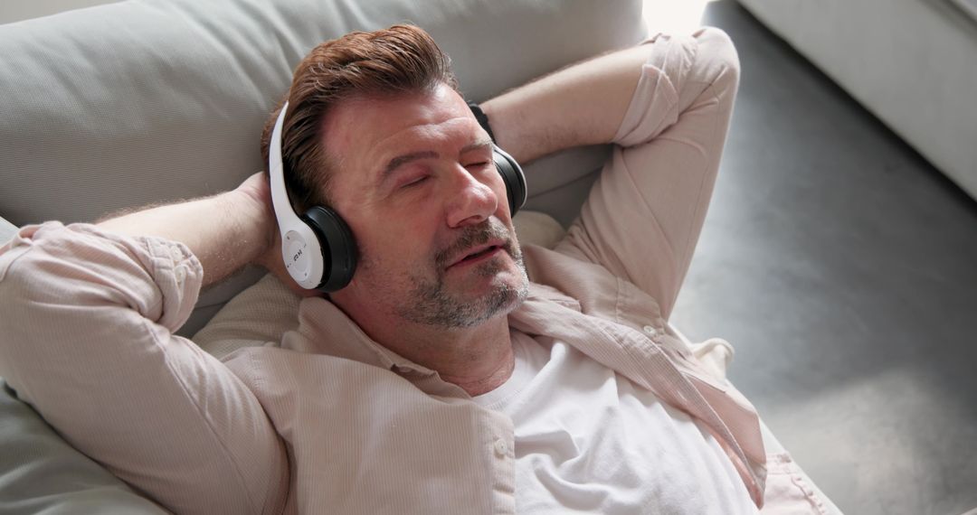 Man Relaxing on Sofa with Headphones Enjoying Music
