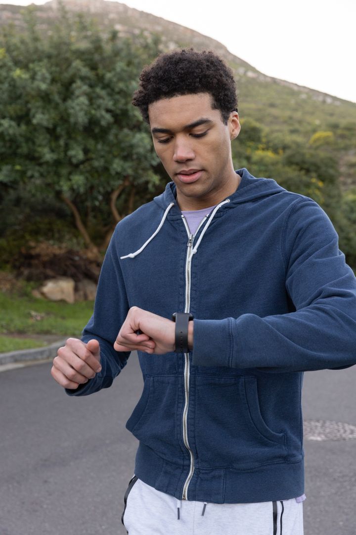 Man Checking Smartwatch During Outdoor Jog on Paved Path