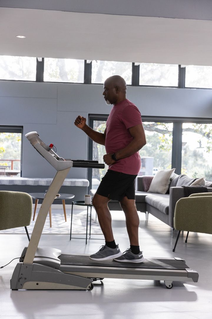 Senior Man Exercising on Treadmill in Modern Living Room