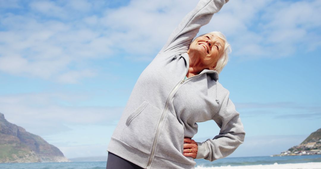 Elderly Woman Exercising on Beach Under Clear Blue Sky - Free Images, Stock Photos and Pictures on Pikwizard.com