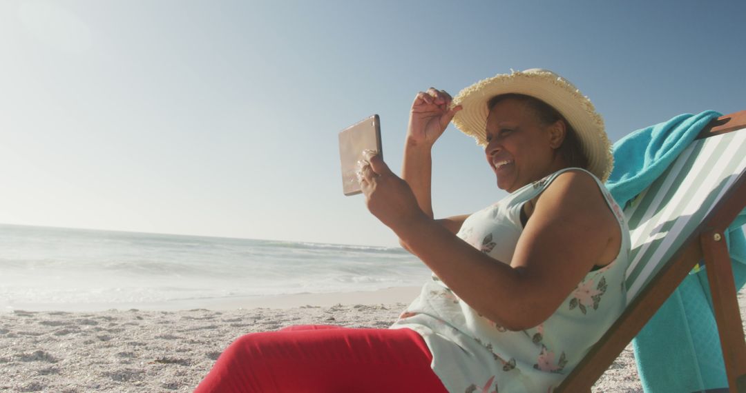 Senior Woman Enjoying Reading on Beach with Tablet - Free Images, Stock Photos and Pictures on Pikwizard.com