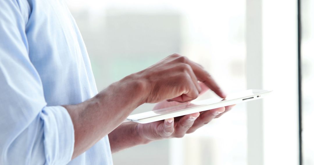 Man using digital tablet by window, close-up of hand - Free Images, Stock Photos and Pictures on Pikwizard.com