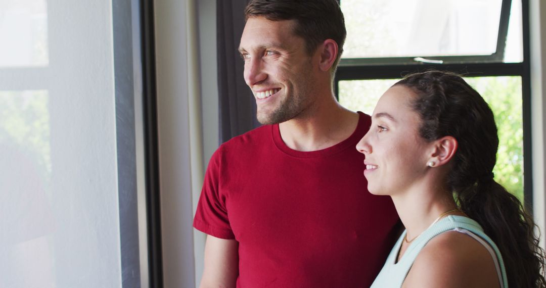 Happy Couple Looking Out Window at Home in Relaxed Atmosphere