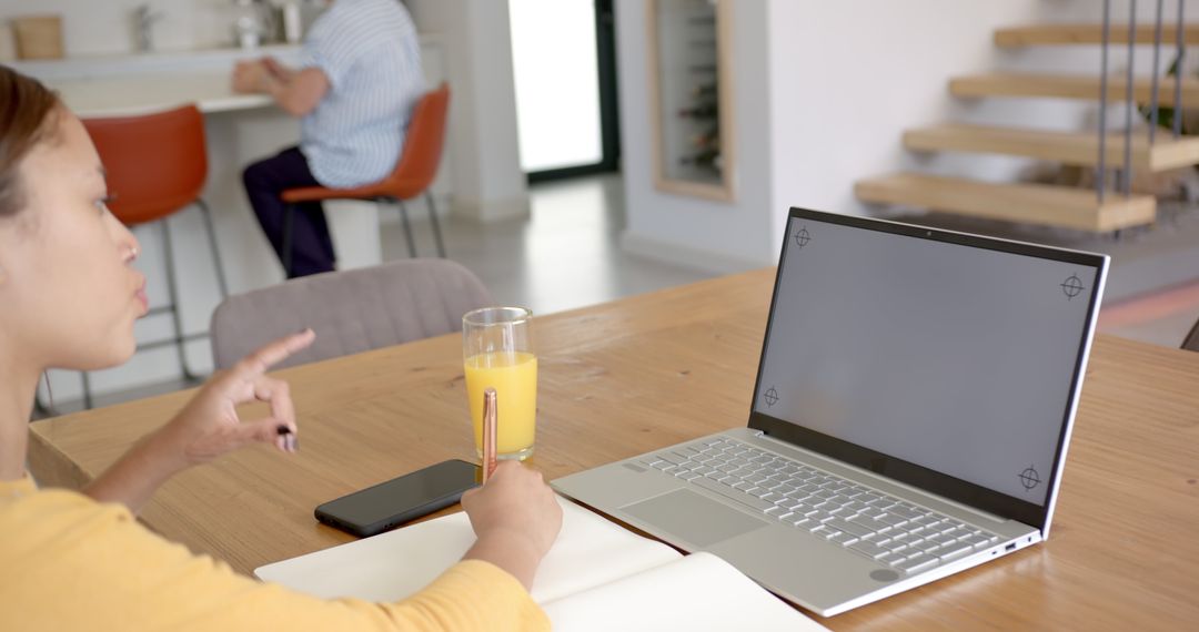 Woman Writing in Notebook with Laptop and Juice at Home