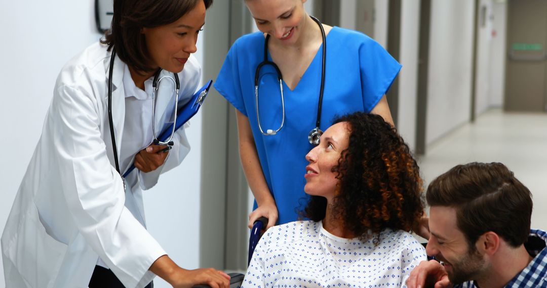 Female doctor and nurse assisting patient in wheelchair with family in hospital corridor. - Free Images, Stock Photos and Pictures on Pikwizard.com