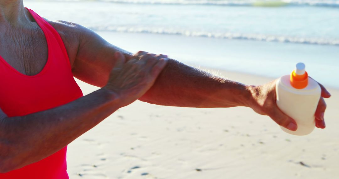 Person Applying Sunscreen on Beach with Sandy Shoreline - Free Images, Stock Photos and Pictures on Pikwizard.com